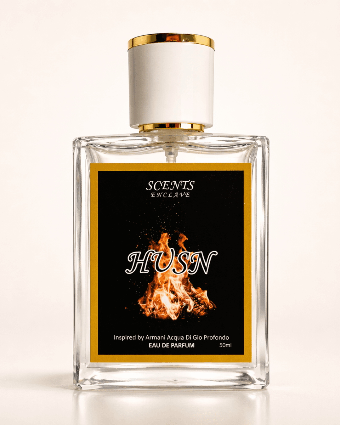 Husn 50ml, Scents Enclave — clear bottle with a gold-rimmed cap and a black label with an orange flame motif