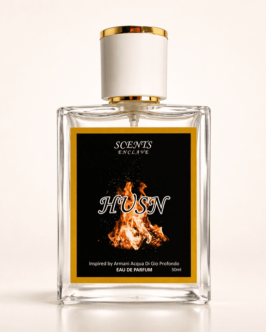 Husn 50ml, Scents Enclave — clear bottle with a gold-rimmed cap and a black label with an orange flame motif